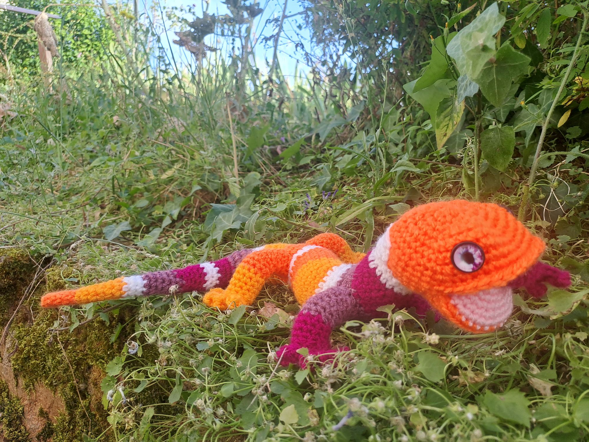 Salamandre au crochet avec des bandes de couleurs orange, blanc et violet. 